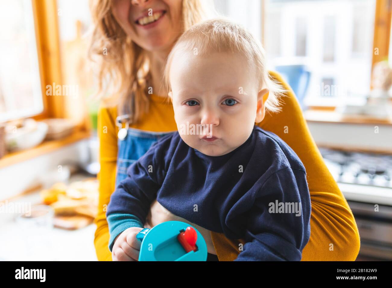 Ritratto del bambino che è tenuto da sua madre che fa il viso divertente Foto Stock