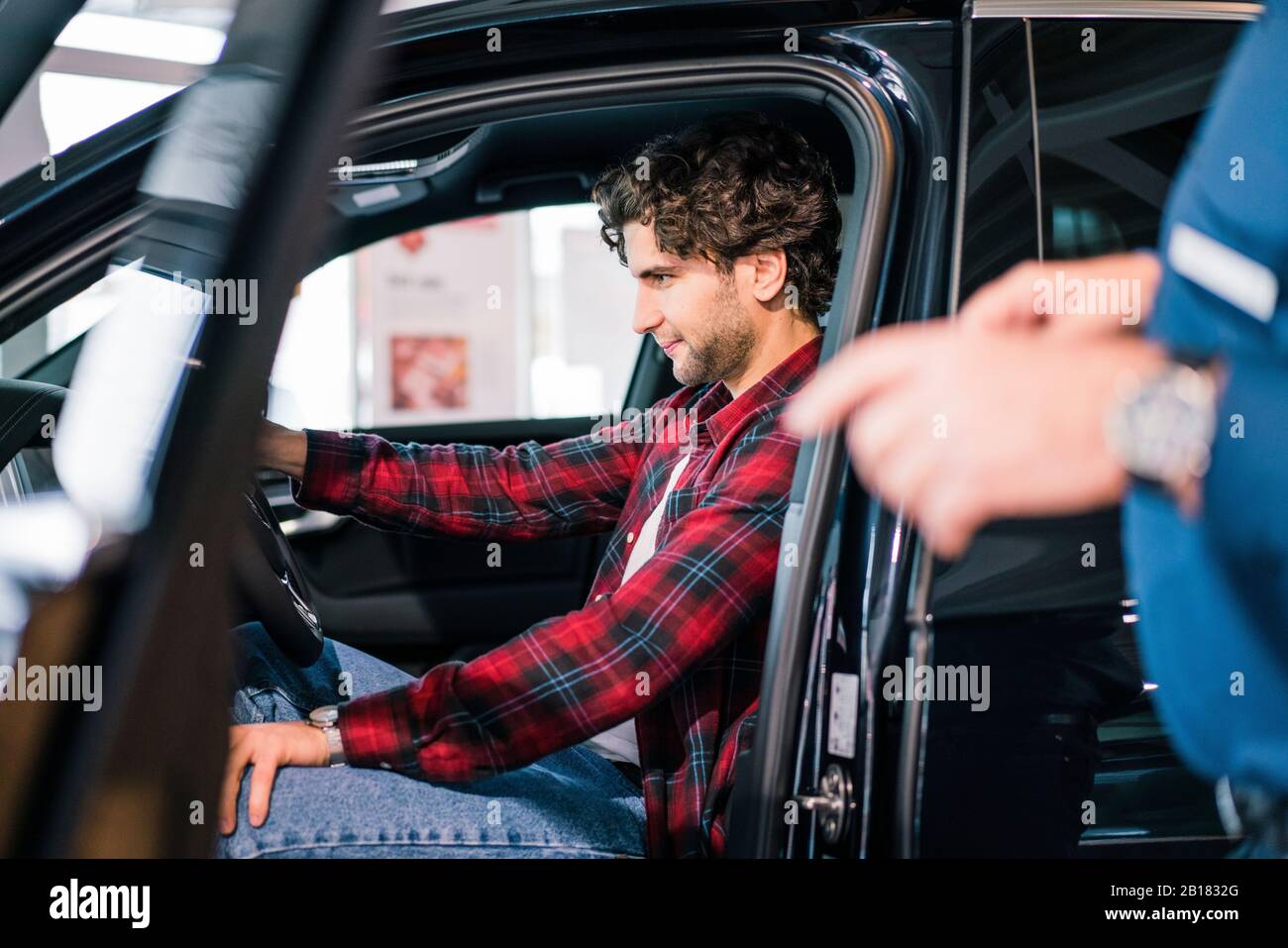 Giovane uomo seduto in auto presso la concessionaria di automobili Foto Stock
