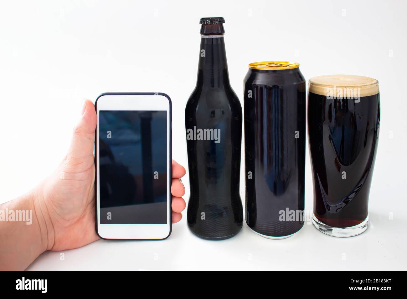 Dublino, Irlanda. 23 Feb 2020. Una persona che tiene un iPhone più con lo schermo dell'app Guinness vicino ad una bottiglia, può e una pinta di Guinness su un backgr bianco Foto Stock