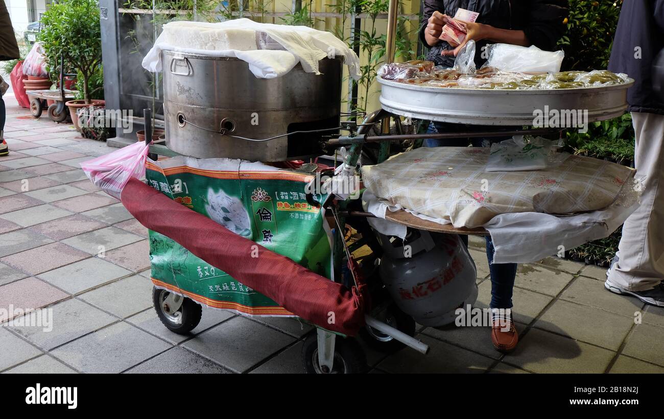 Taipei, TAIWAN - 07 dicembre 2019: Un fornitore che vende torte e pasticcini al vapore su un carrello su ruote, sulla strada di Taipei. Foto Stock