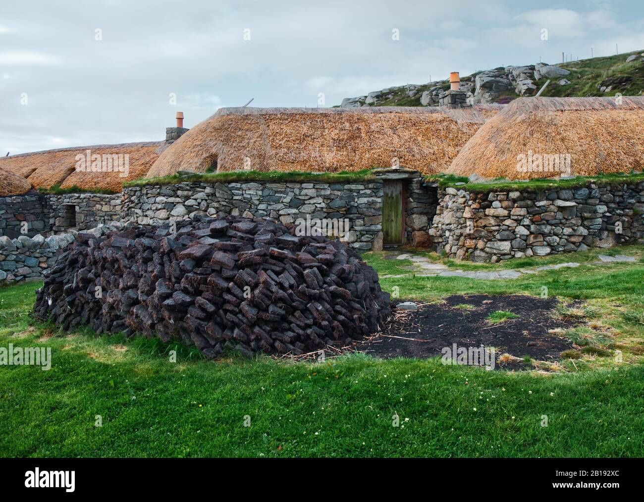 Pila di torba che asciuga fuori del villaggio di Gearrannan Blackhouse cottage in pietra, Isola di Lewis, Ebridi esterne, Scozia Foto Stock
