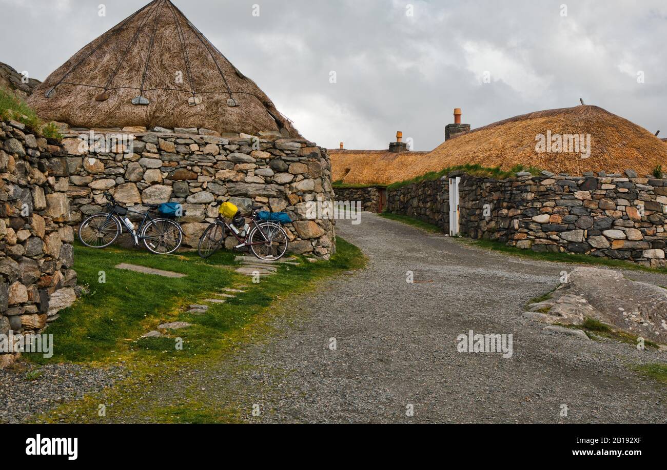 Due biciclette da turismo fuori dei cottage in pietra del villaggio di Gearrannan Blackhouse, Isola di Lewis, Ebridi esterne, Scozia Foto Stock