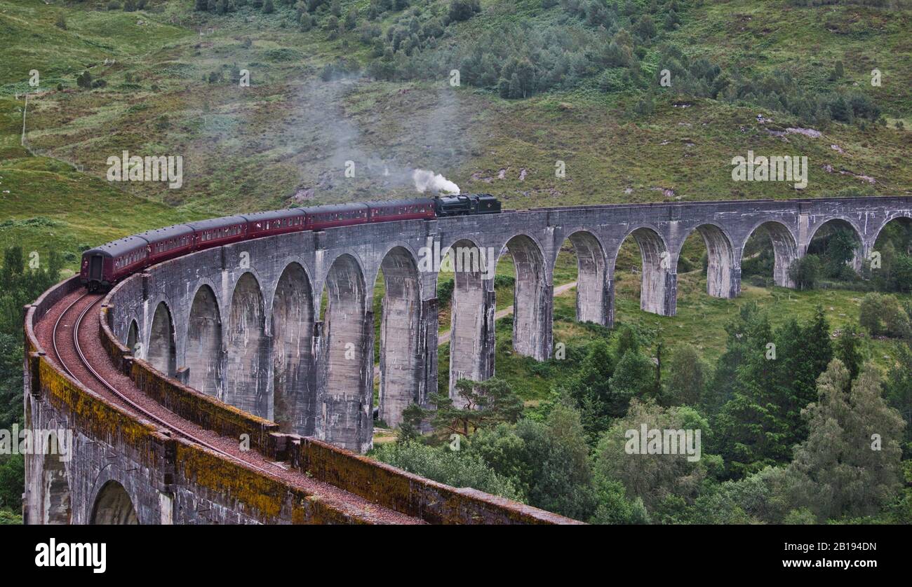 Il treno a vapore Jacobite che soffia vapore ad esso attraversa il Viadotto di Glenfinnan, Glenfinnan, Inverness-shire, Scozia Foto Stock