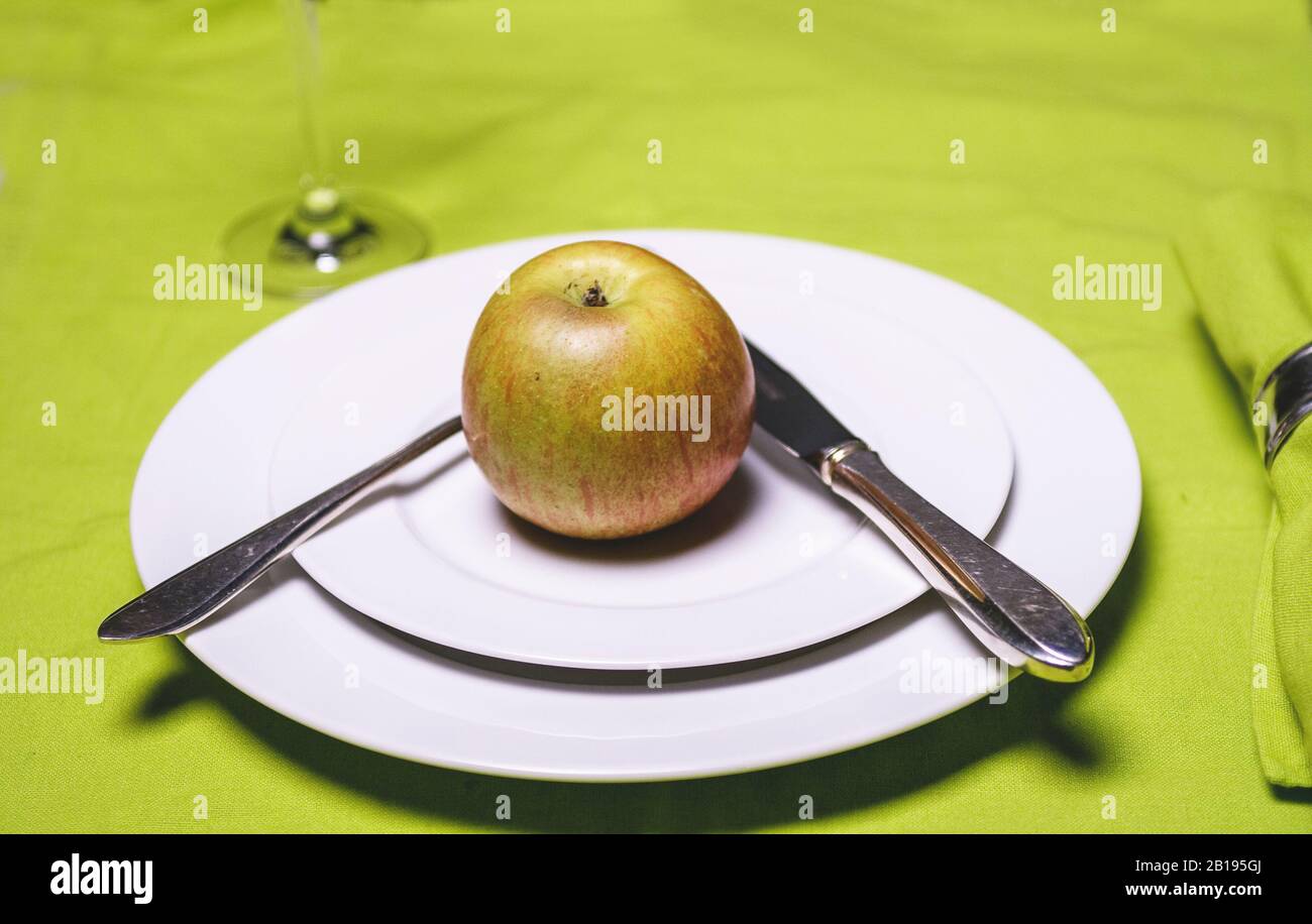 Apple su piastra con coltello e forchetta e vetro su applegreen tovaglia Foto Stock
