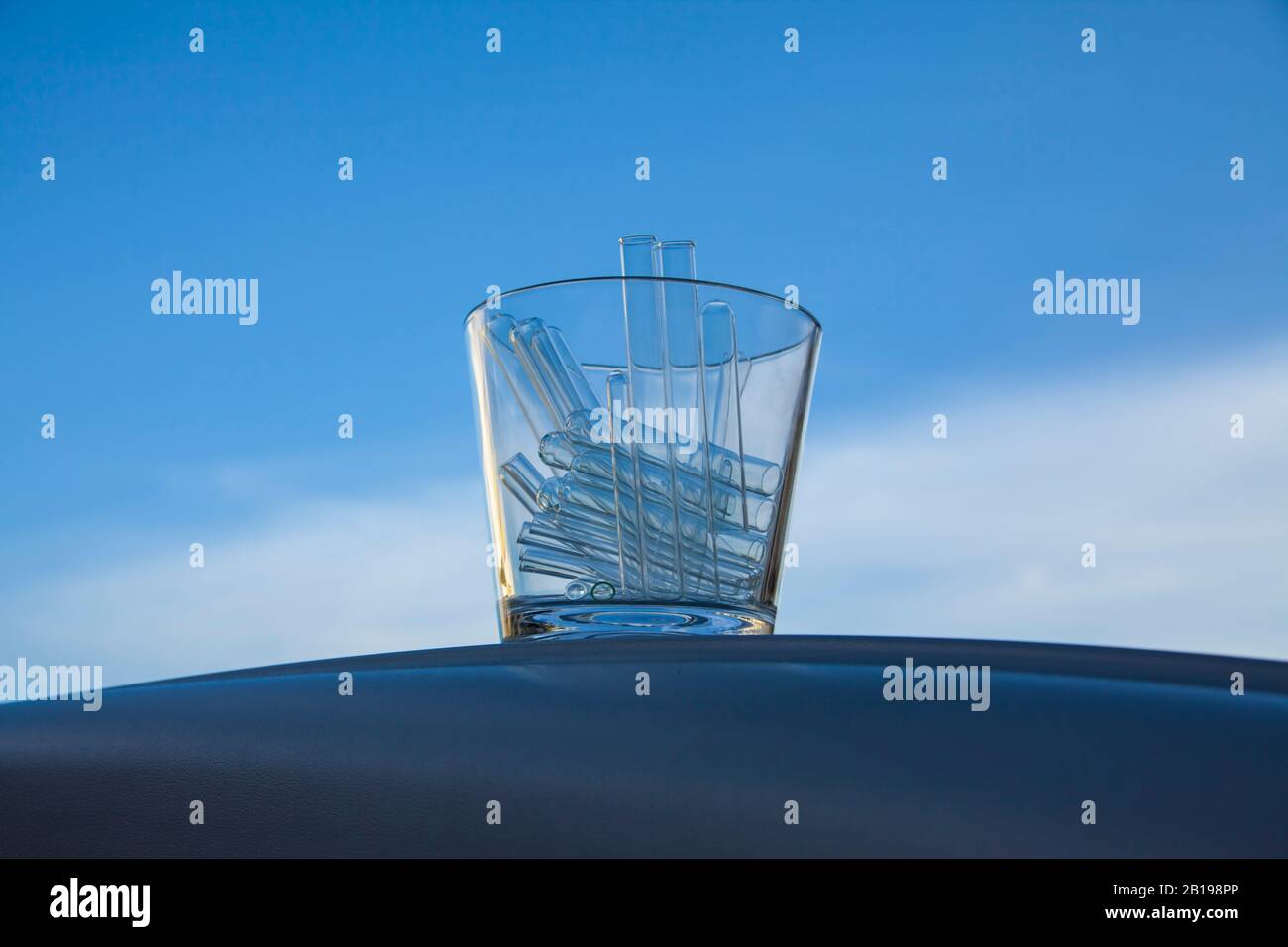 contenitore di vetro pieno di provette di vetro vuote fotografate sul cielo come sfondo Foto Stock