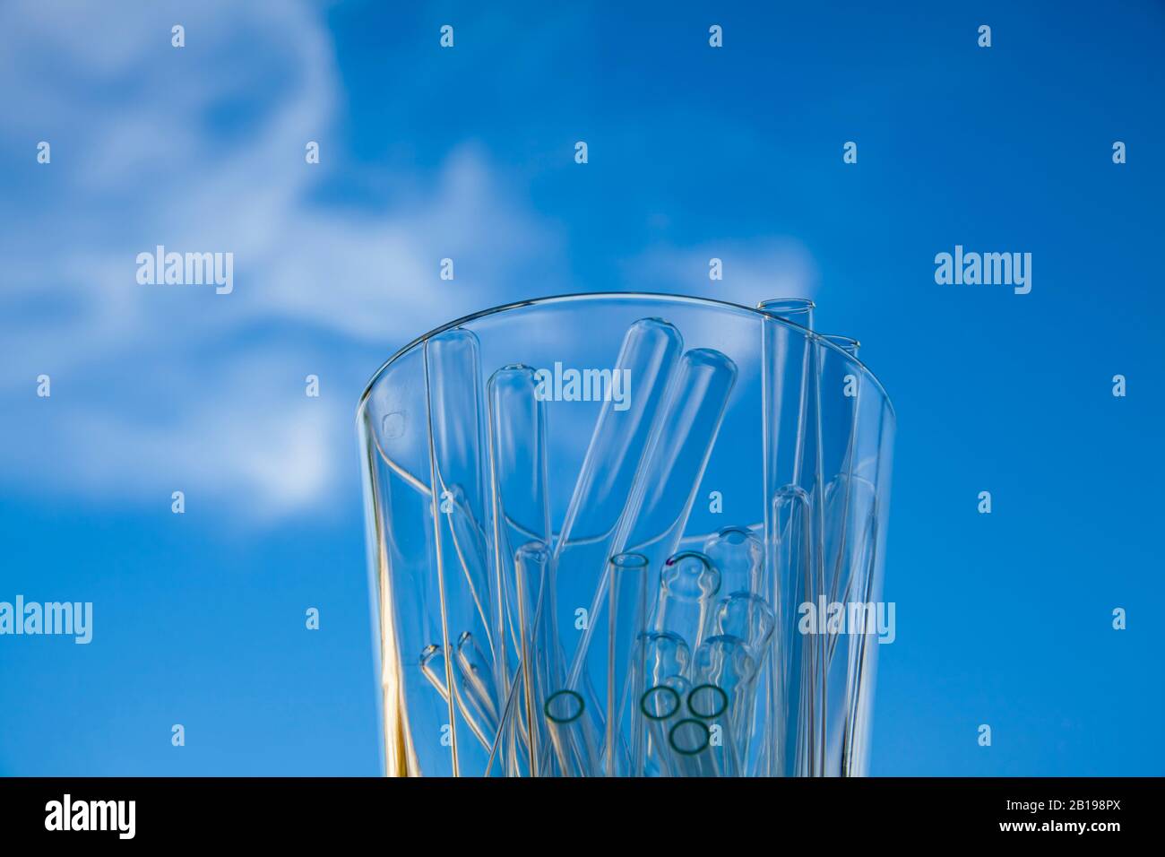 contenitore di vetro pieno di provette di vetro vuote fotografate sullo sfondo del cielo Foto Stock