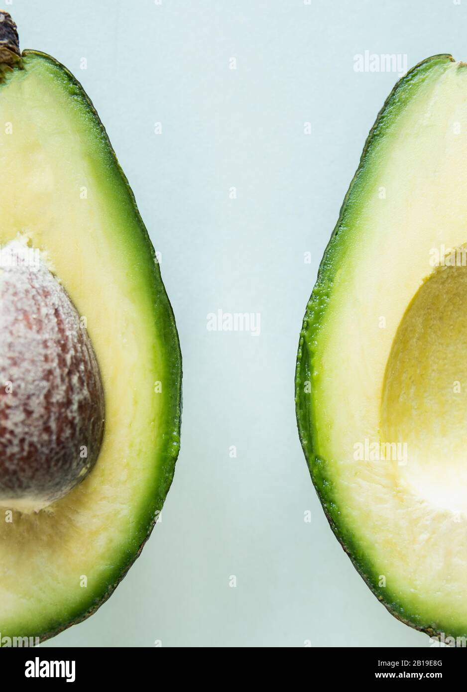Pronto a mangiare avocado tagliato in due metà, isolato su sfondo verde chiaro. Foto Stock