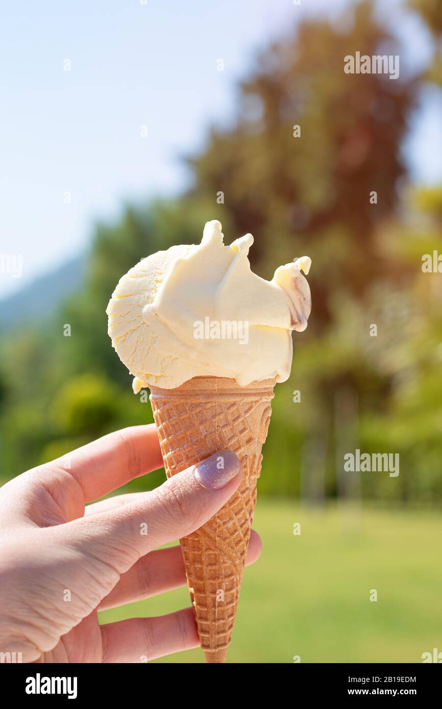 Cono gelato giallo in mano femmina Foto Stock