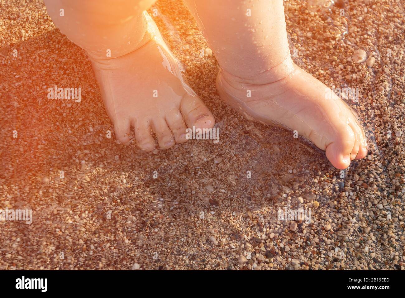 Baby piedi sul mare ciottoli sulla luce del sole. Foto Stock
