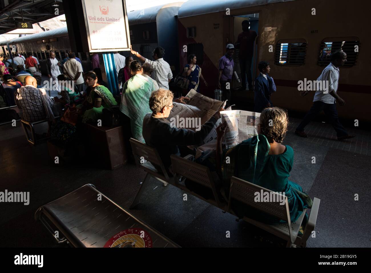 Lettura giornale, in attesa del treno. Stazione ferroviaria di Tirupati, Andhra Pradesh. India del Sud. Foto Stock