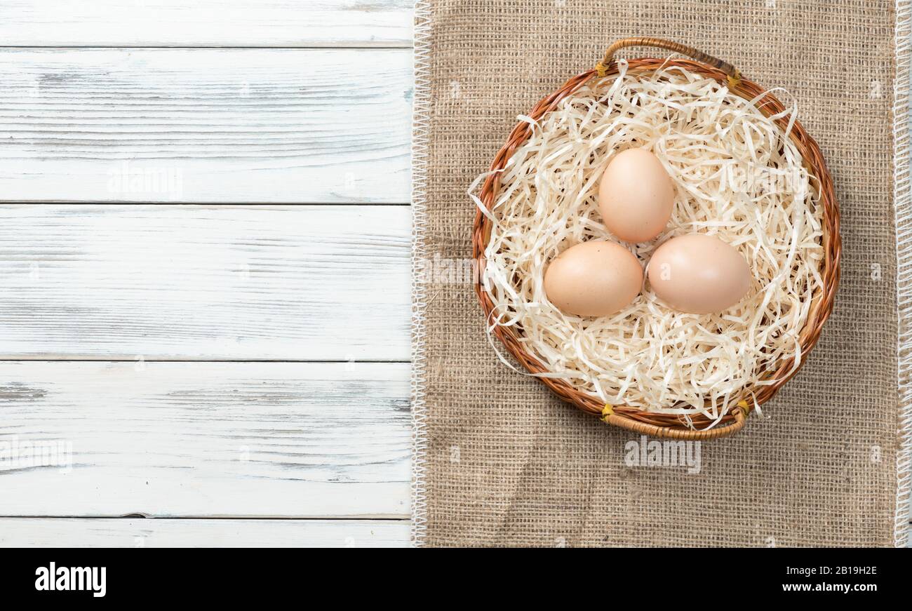 Uova di pollo di Pasqua in un nido su uno sfondo di legno Foto Stock