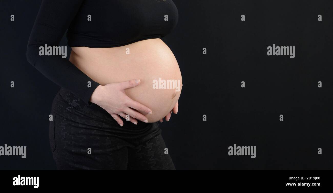 Donna incinta con le mani sul ventre. Parte del corpo. Foto Stock