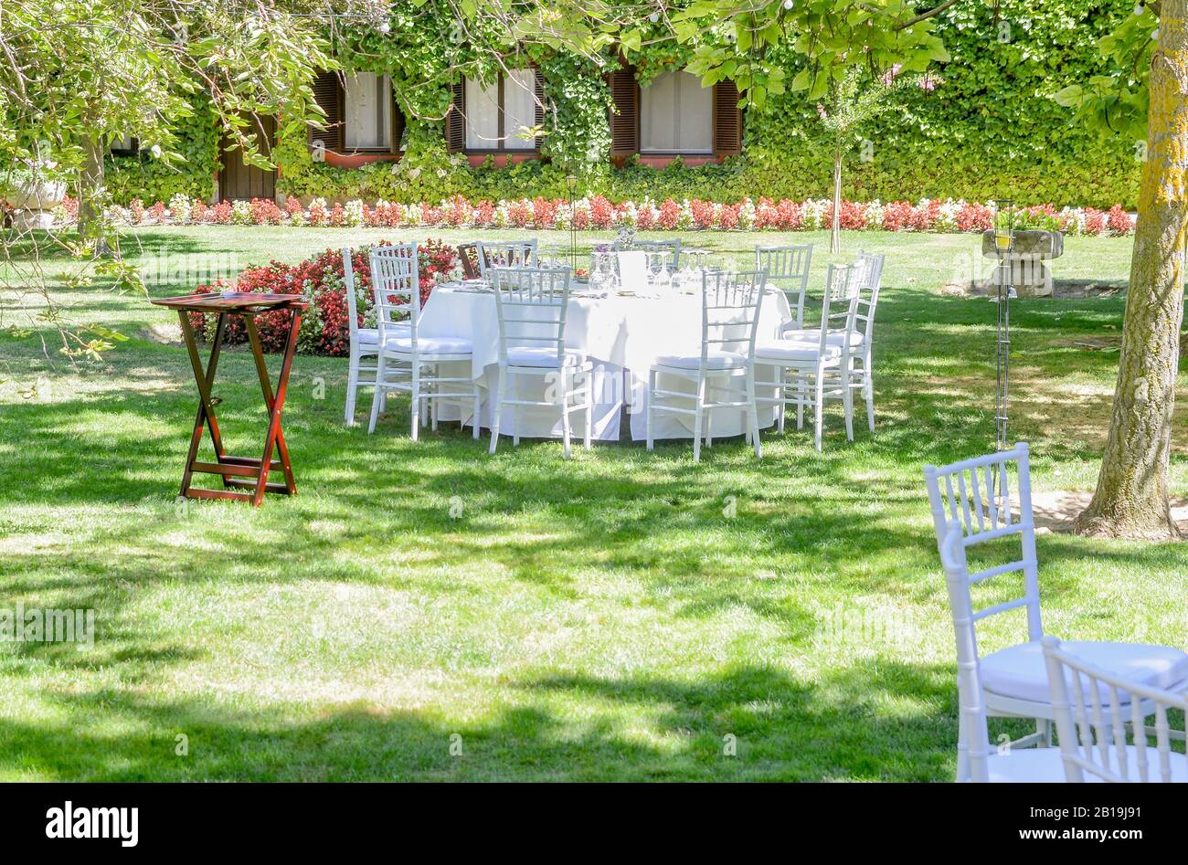 Mobili con tavolo bianco e sedie in giardino in una giornata di sole. Foto Stock