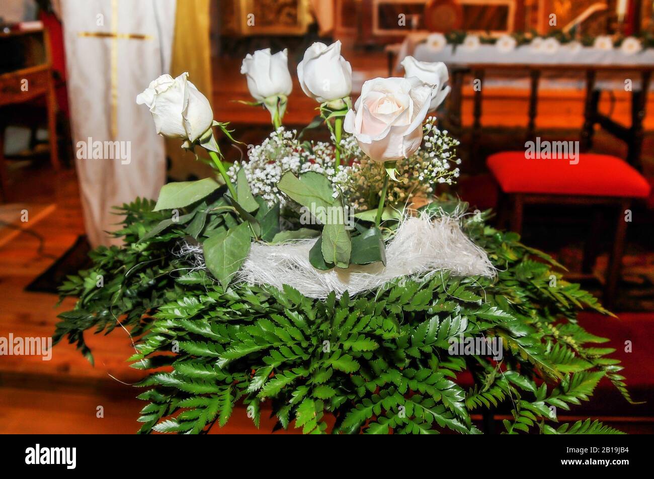 Ornamento con rose bianche e foglie verdi all'interno di una chiesa per decorare una celebrazione. Foto Stock