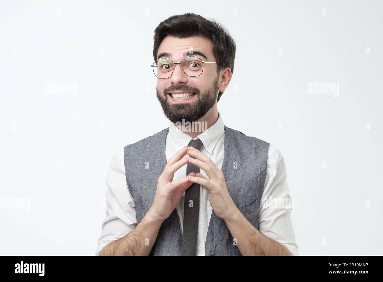 Timido giovane ispanico che chiede un favore o aiuto sorridente. Studio. Concetto piatto o fawn Foto Stock