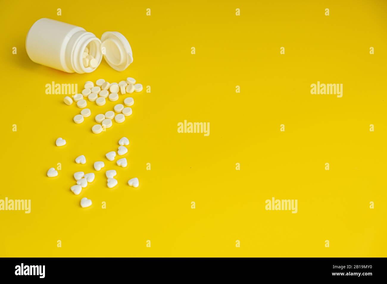 Pillole bianche e bottiglia bianca su uno sfondo giallo brillante, sano e concetto di medicina. Minimalismo. Spazio di copia Foto Stock