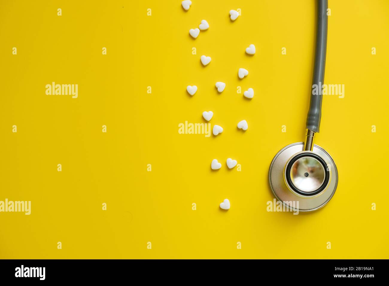 Stetoscopio medico e pillole di cuore bianco su sfondo giallo salute minimalismo concetto Foto Stock