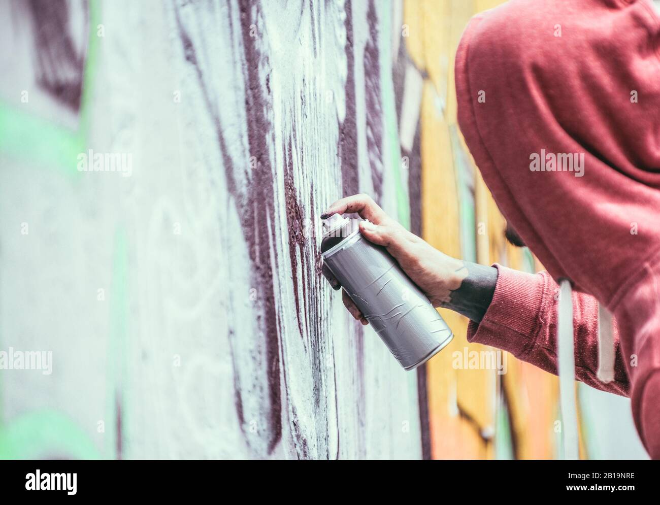 Tattoo graffiti scrittore pittura con colore spray la sua immagine scura sul muro - artista contemporaneo al lavoro - stile di vita urbano, Street art concept - Foc Foto Stock