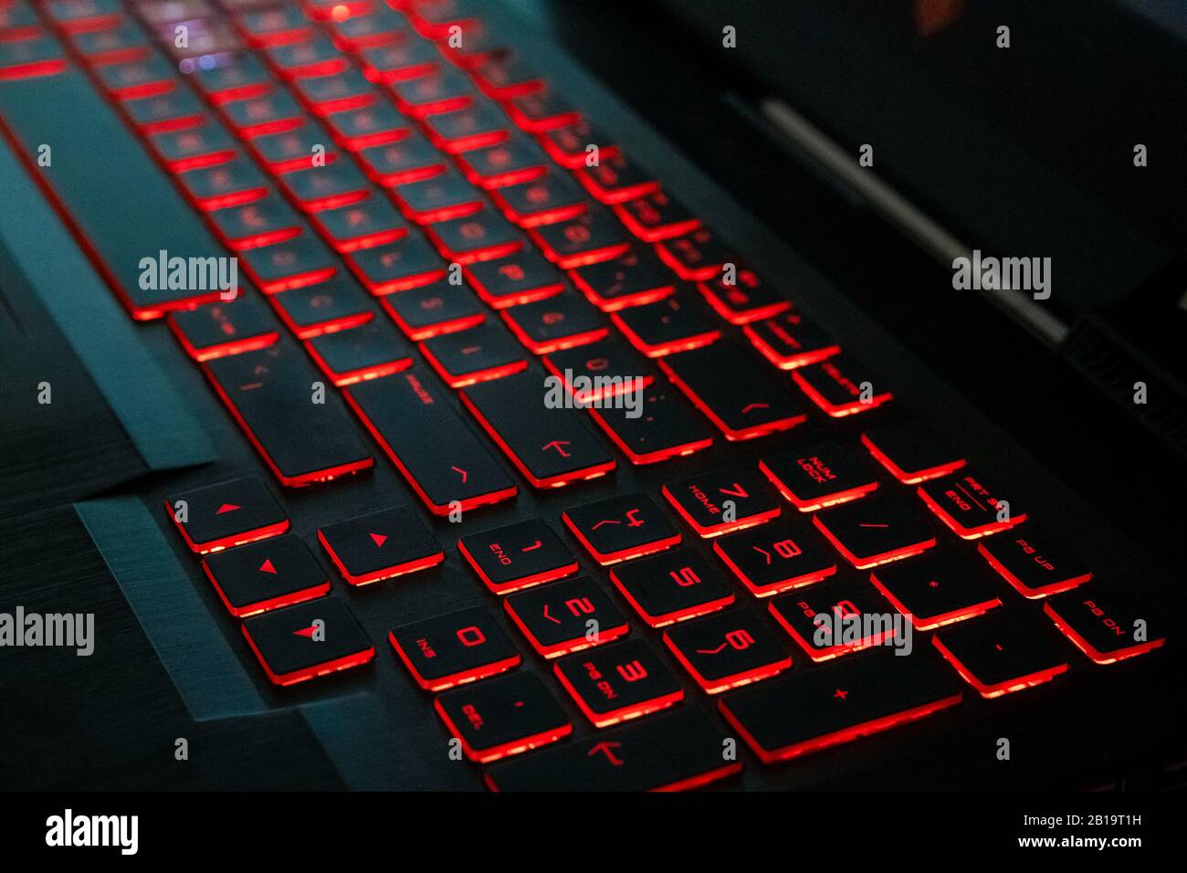 Primo piano di un moderno computer portatile tastiera tasti. Illuminazione soffusa in toni rossi. Foto Stock