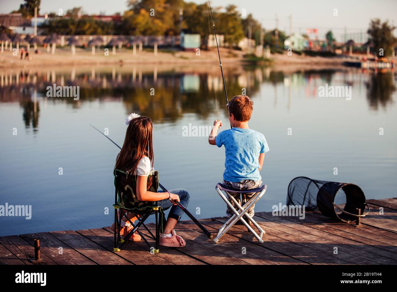 Due piccoli amici simpatici, ragazzo e ragazza che pescano su un lago in una soleggiata giornata estiva. I bambini stanno giocando. Amicizia. Foto Stock