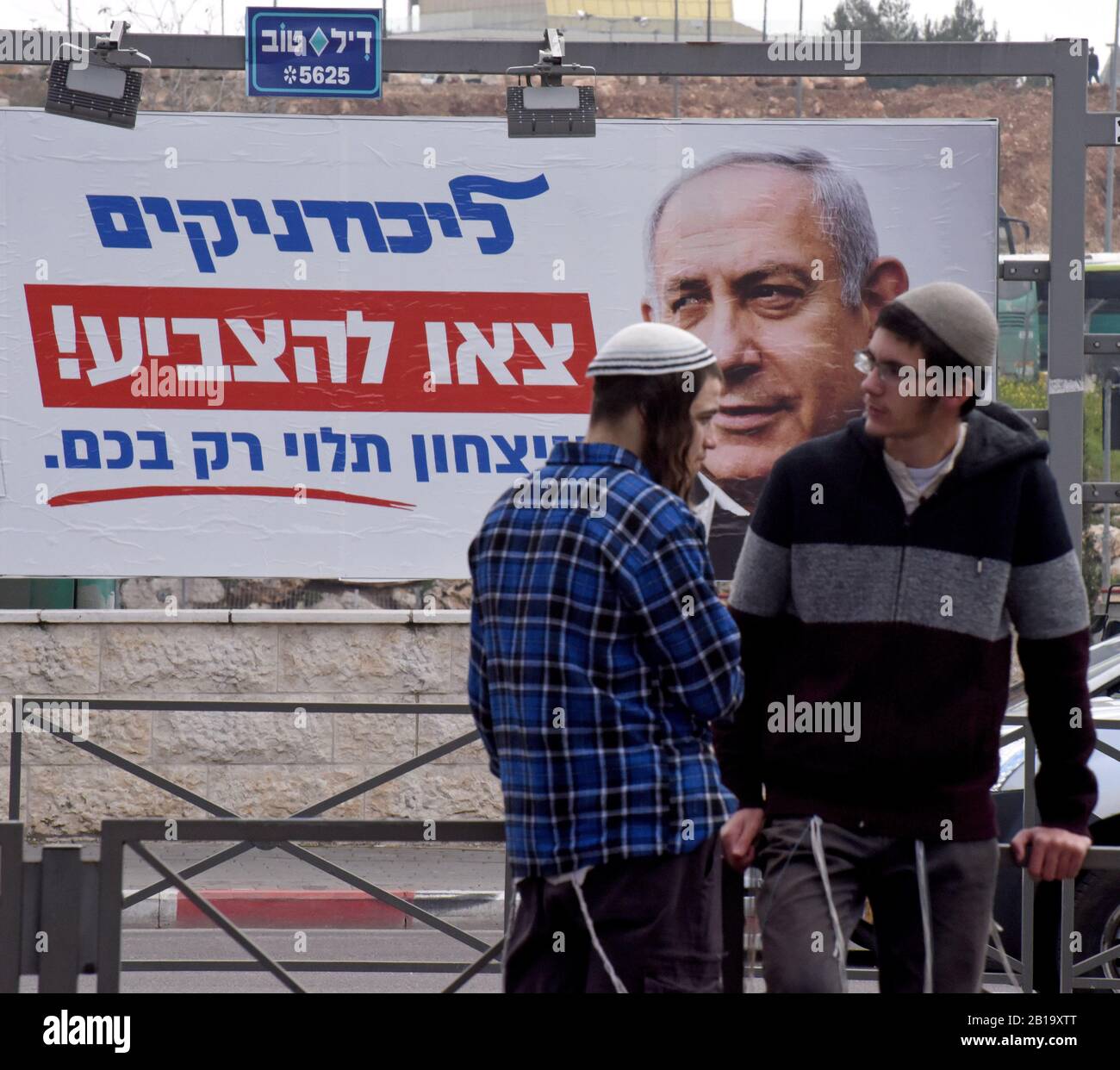 Gerusalemme, Israele. 24th Feb, 2020. I coloni israeliani si trovano di fronte a un poster della campagna elettorale per il primo ministro israeliano Benjamin Netanyahu, lunedì 24 febbraio 2020, a Gerusalemme, Israele. Il poster esorta i membri del Partito Likud di Netanyahu a "Votare". Gli israeliani si dirigono alle urne il 2 marzo per la terza elezione a meno di un anno. Foto di Debbie Hill/UPI Credit: UPI/Alamy Live News Foto Stock