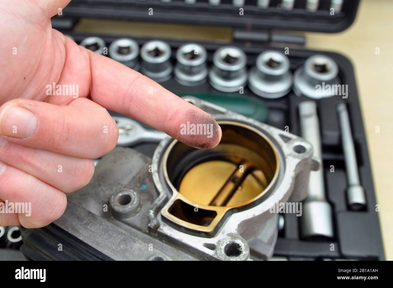 Riparare e pulire l'acceleratore del veicolo. Acceleratore con tracce di bruciature e fuliggine sullo sfondo di una serie di attrezzi per la riparazione di automobili Foto Stock