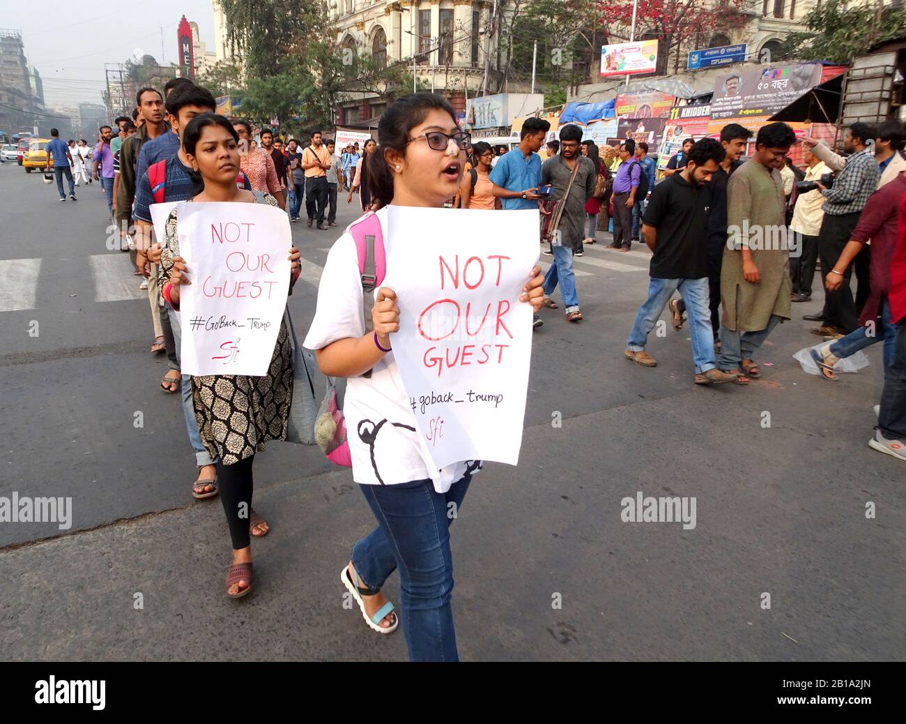 I sostenitori degli studenti hanno dei cartelli che dicono di non essere nostri ospiti durante una dimostrazione contro la visita ufficiale del presidente americano Donald Trump in India. Foto Stock