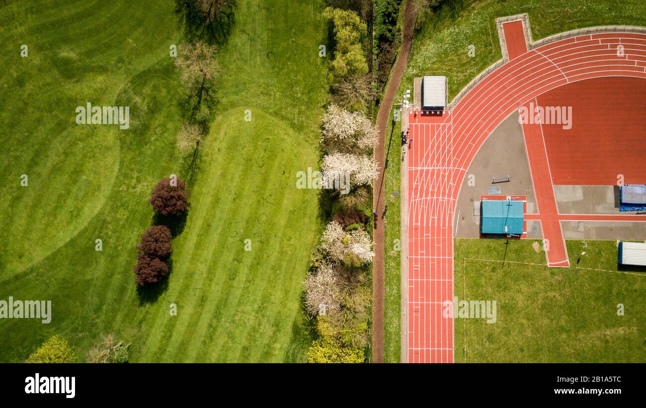 Traccia e Campo. Veduta aerea astratta che guarda giù su una pista da corsa professionale di atletica contro il verde di un campo da golf vicino. Foto Stock