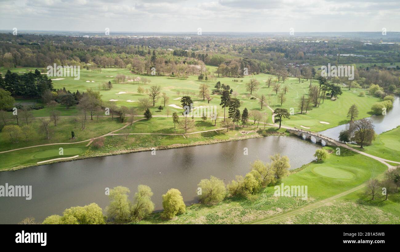 La campagna sud-inglese in una luminosa giornata primaverile con un ponte di pietra che attraversa un fiume verso un campo da golf. Vista aerea del drone. Foto Stock