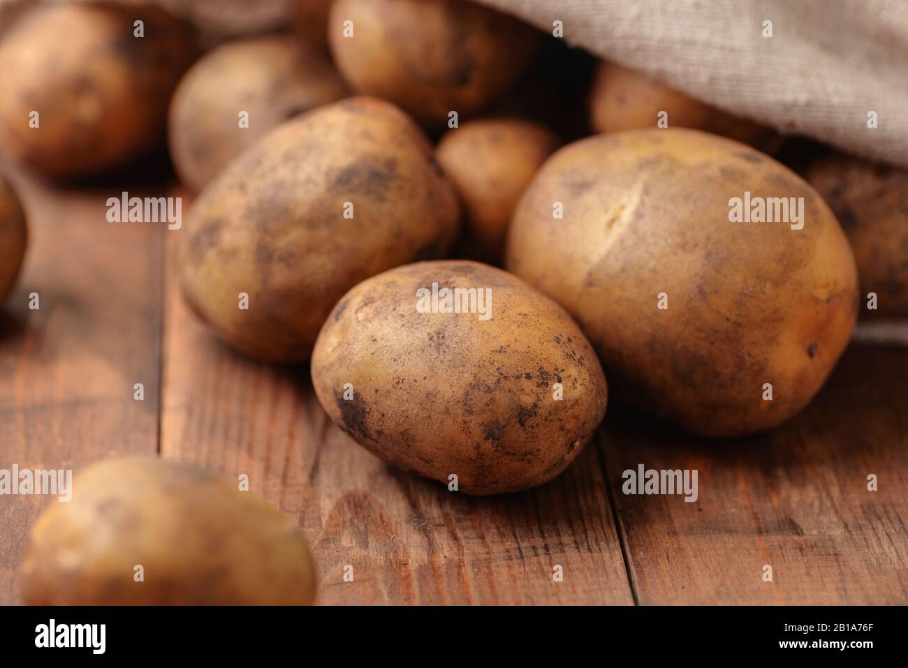 Primo piano di patate biologiche crude fresche su tavola di legno Foto Stock