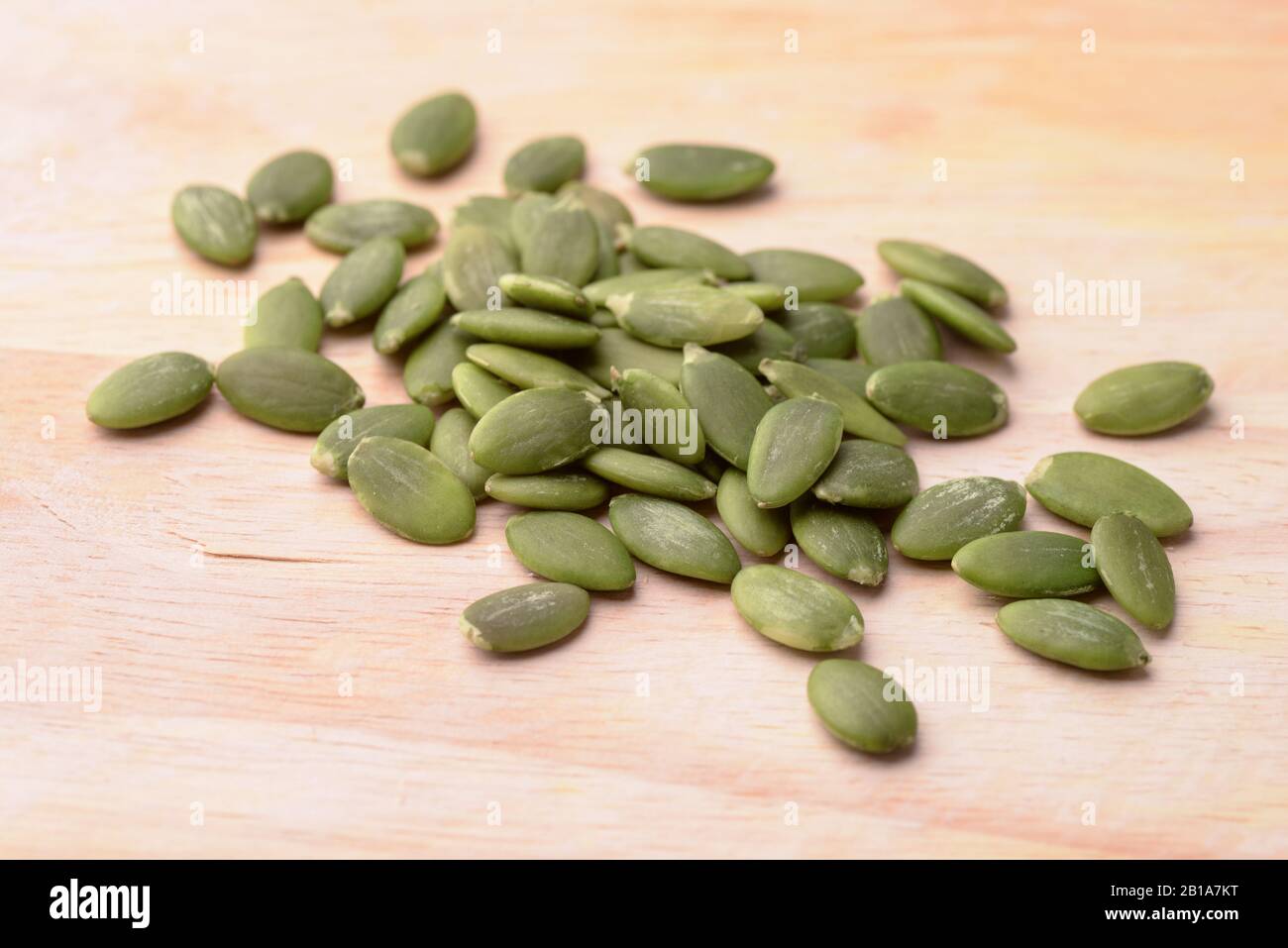 Semi di zucca verdi sgusciati su sfondo di legno Foto Stock