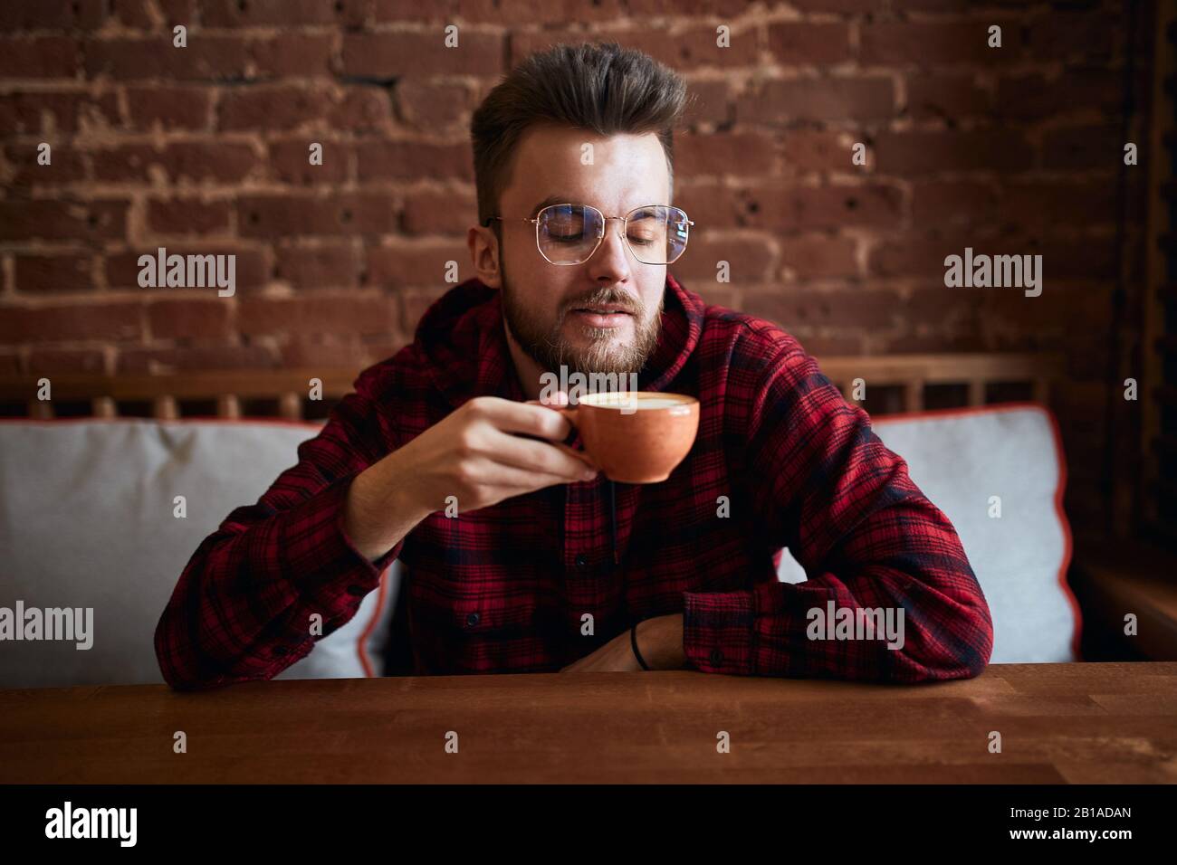 giovane bearded che tiene una tazza di caffè meraviglioso che guarda la bevanda, l'arte, la foto di primo piano. divertimento, rilassamento.amante del caffè Foto Stock