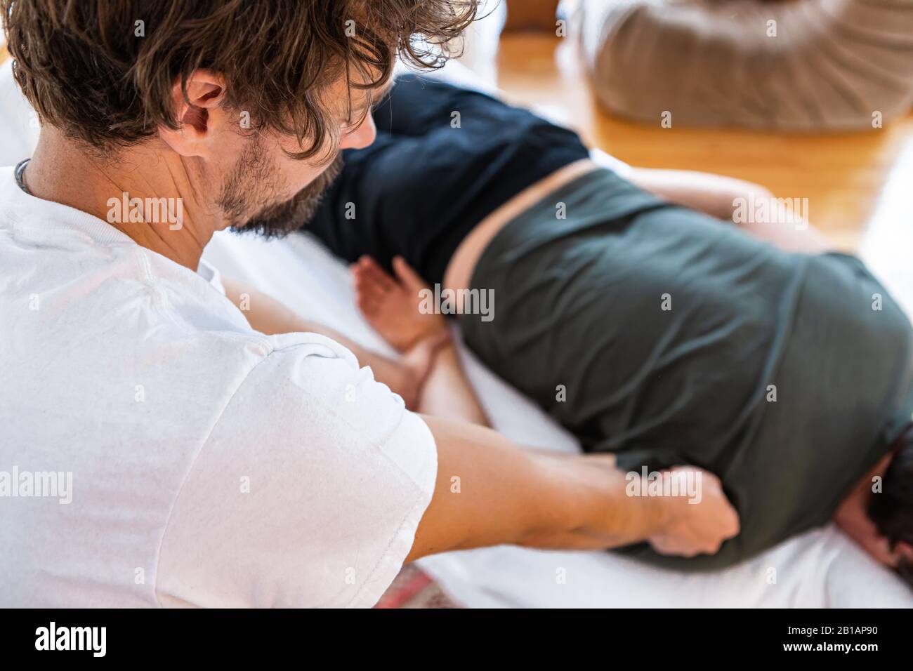 Un fisioterapista irriconoscibile che massaggia un paziente sportivo maschio con il muscolo posteriore ferito. Trattamento delle lesioni sportive. Vista dall'alto Foto Stock