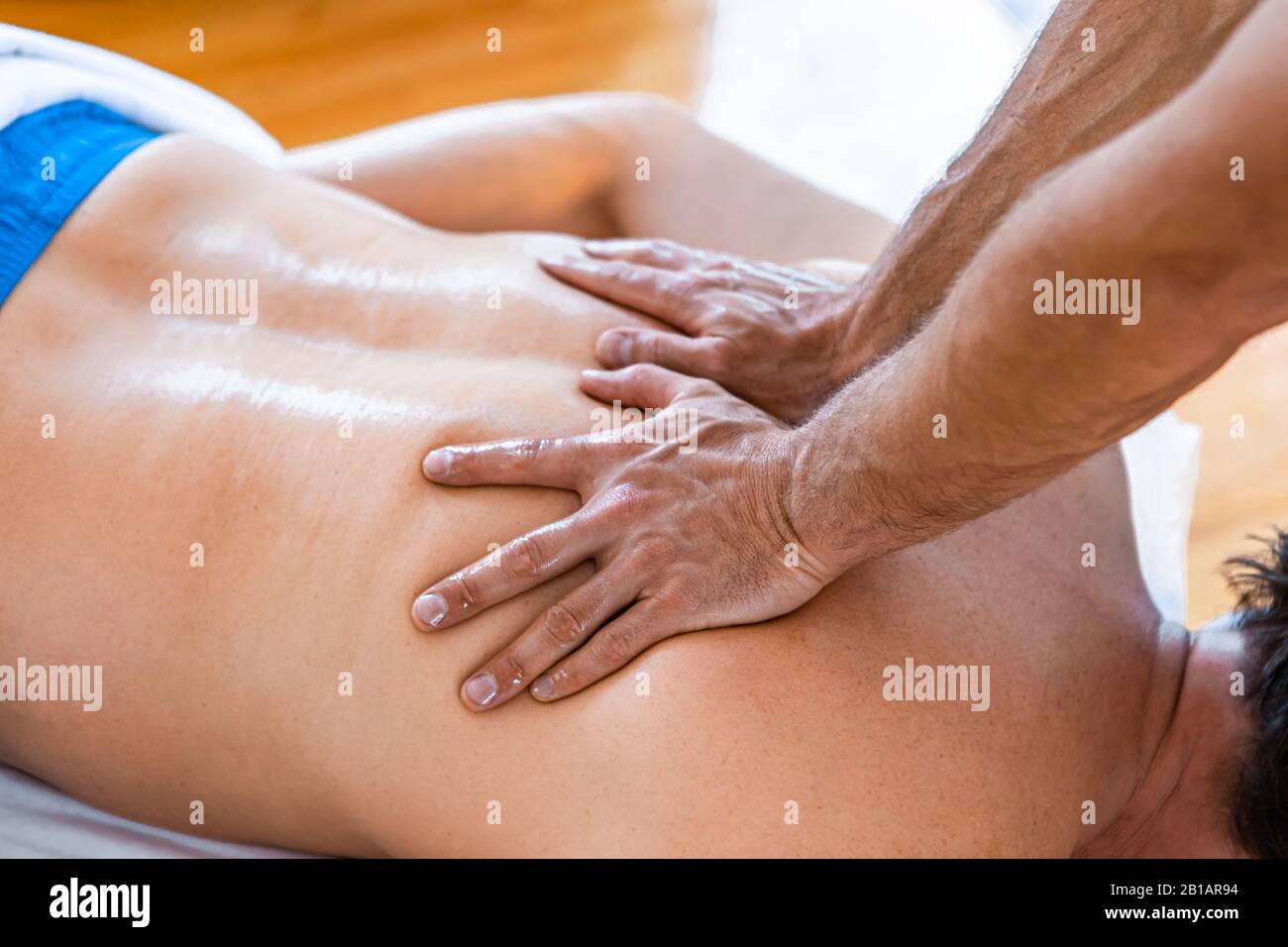 Un uomo che riceve un trattamento di massaggio. Primo piano di mani massaggiatrici e un cliente indietro. Uomo che ottiene un massaggio rilassante nel centro termale Foto Stock