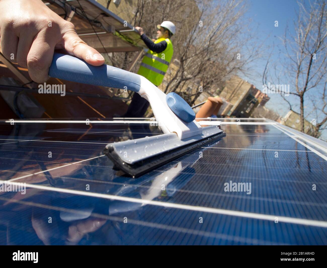 Pannelli solari per la pulizia a mano con un detergente per vetri e tecnici esperti caucasici che puliscono i pannelli solari con un panno. Elettricità alternativa Foto Stock