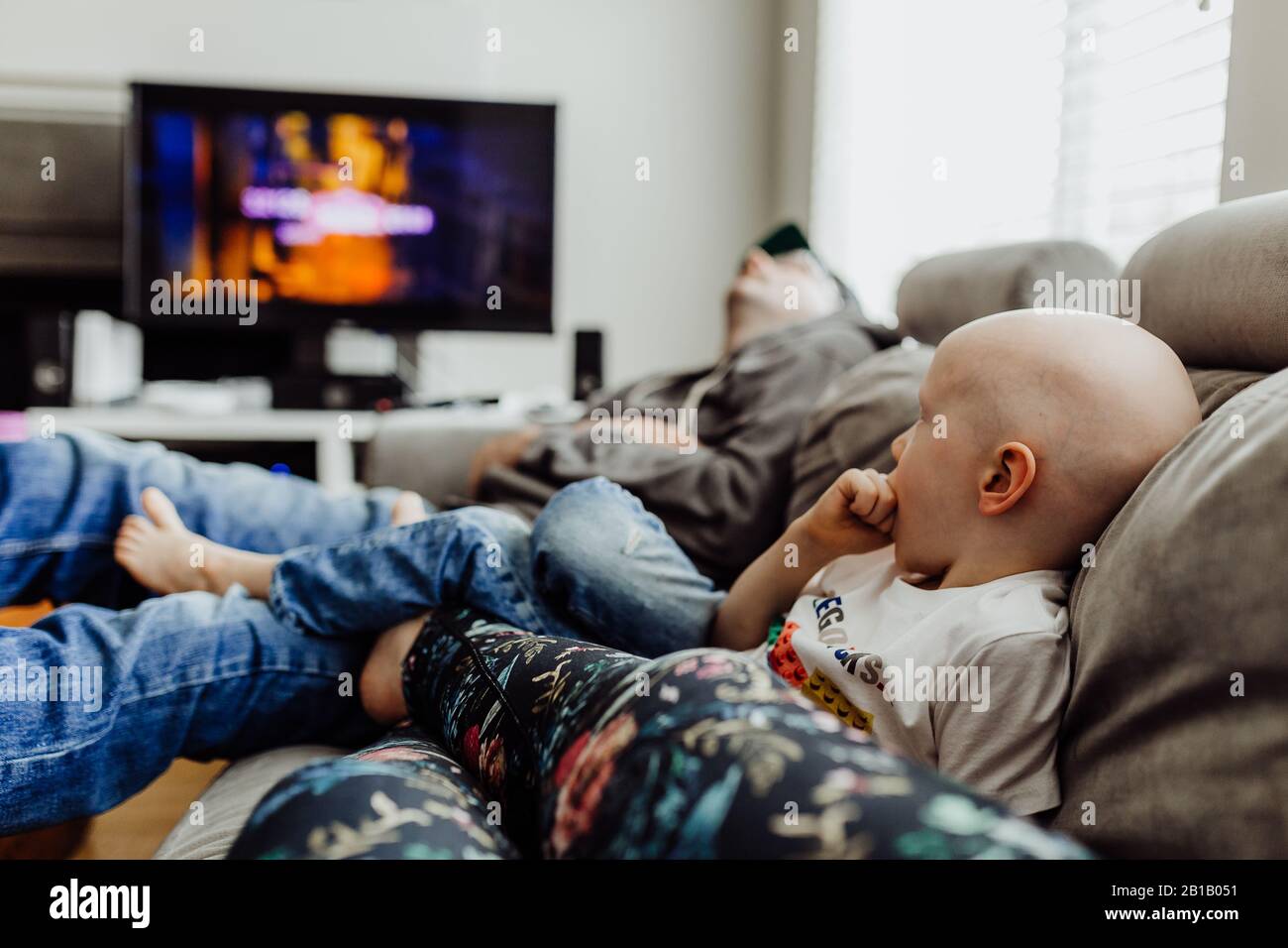 La famiglia si rilassa sul divano guardando la tv mentre papà pisse Foto Stock