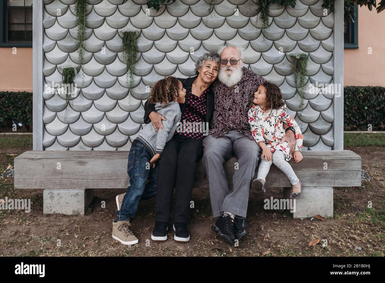 Ritratto dei nonni seduti con i bisnonni carini fuori Foto Stock