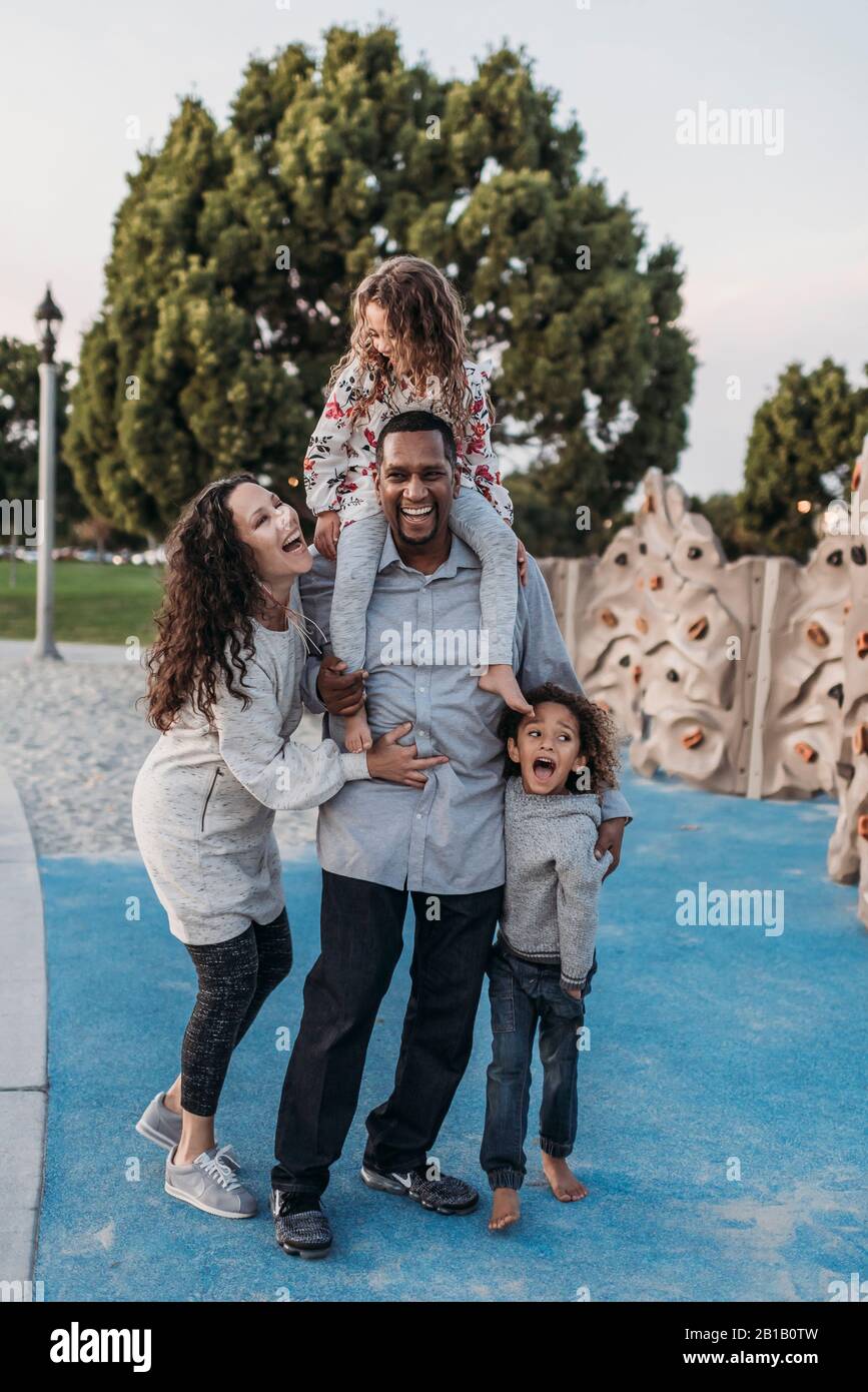 Immagine di stile di vita di bella famiglia felice che gioca nel parco al tramonto Foto Stock