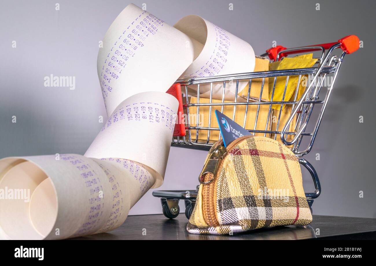 Concetto di shopping: Un modello carrello di shopping pieno di pacchi, con un lungo rotolo di spesa che fuoriesce, e una carta di credito / debito in una borsa. Foto Stock
