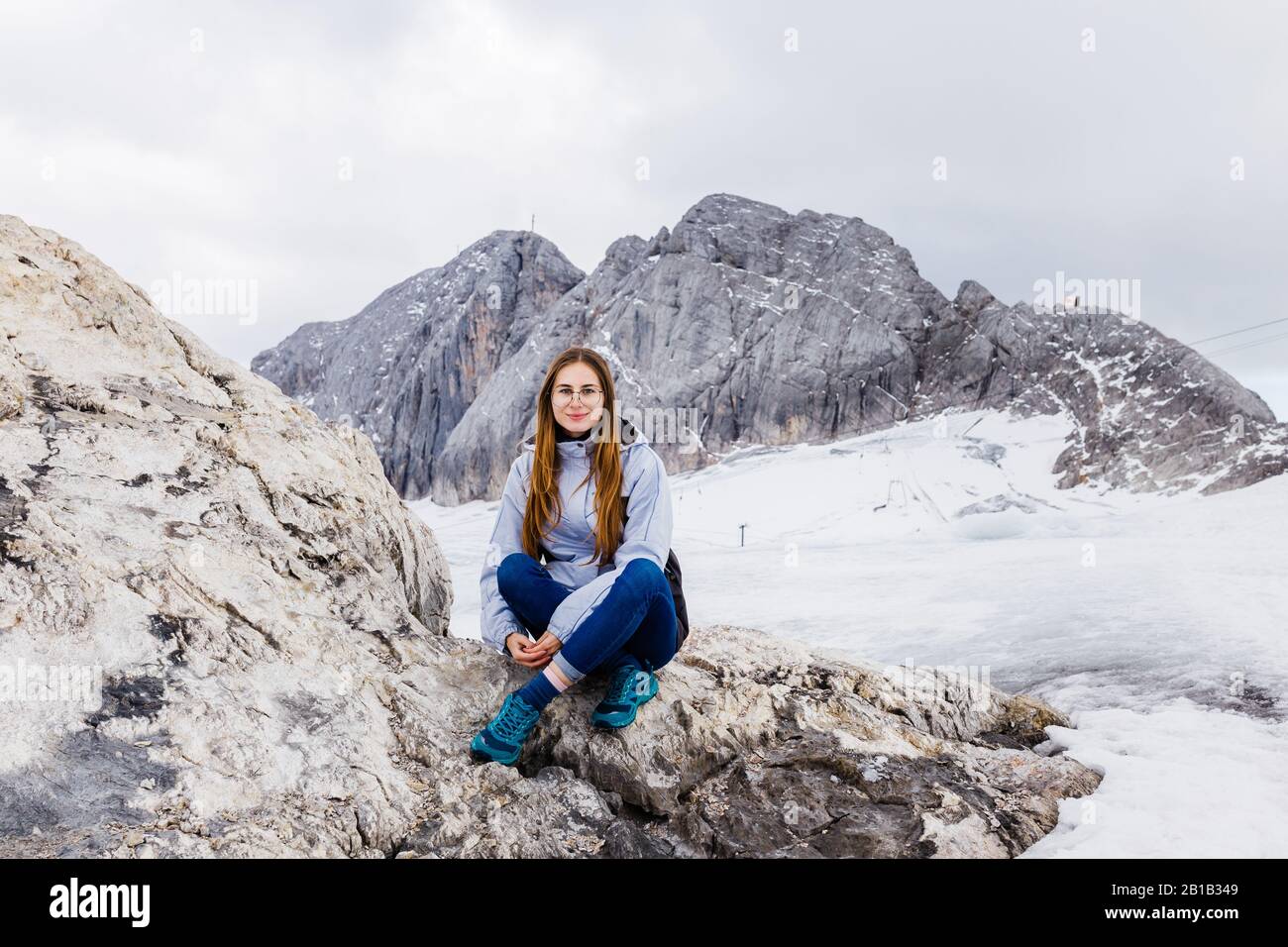 Giovane ragazza millenaria gode della vista sulle Alpi che si erpano sul ghiacciaio Foto Stock