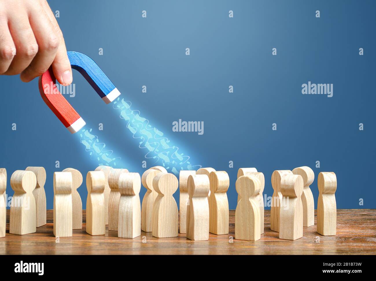 La mano con un magnete attrae i soldi dalle persone. Riscossione delle imposte. Crowdfunding, trovare finanziamenti per le imprese startup. Frode phishing, appropriazione indebita. Foto Stock