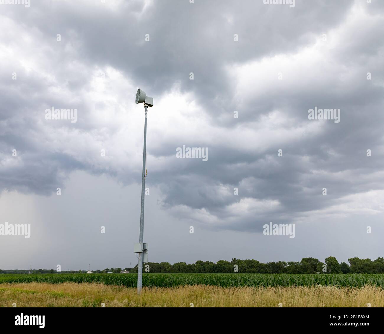 Grave allarme meteo e sirena di tornado lungo la strada rurale con nuvole buie tempesta e pioggia in background Foto Stock