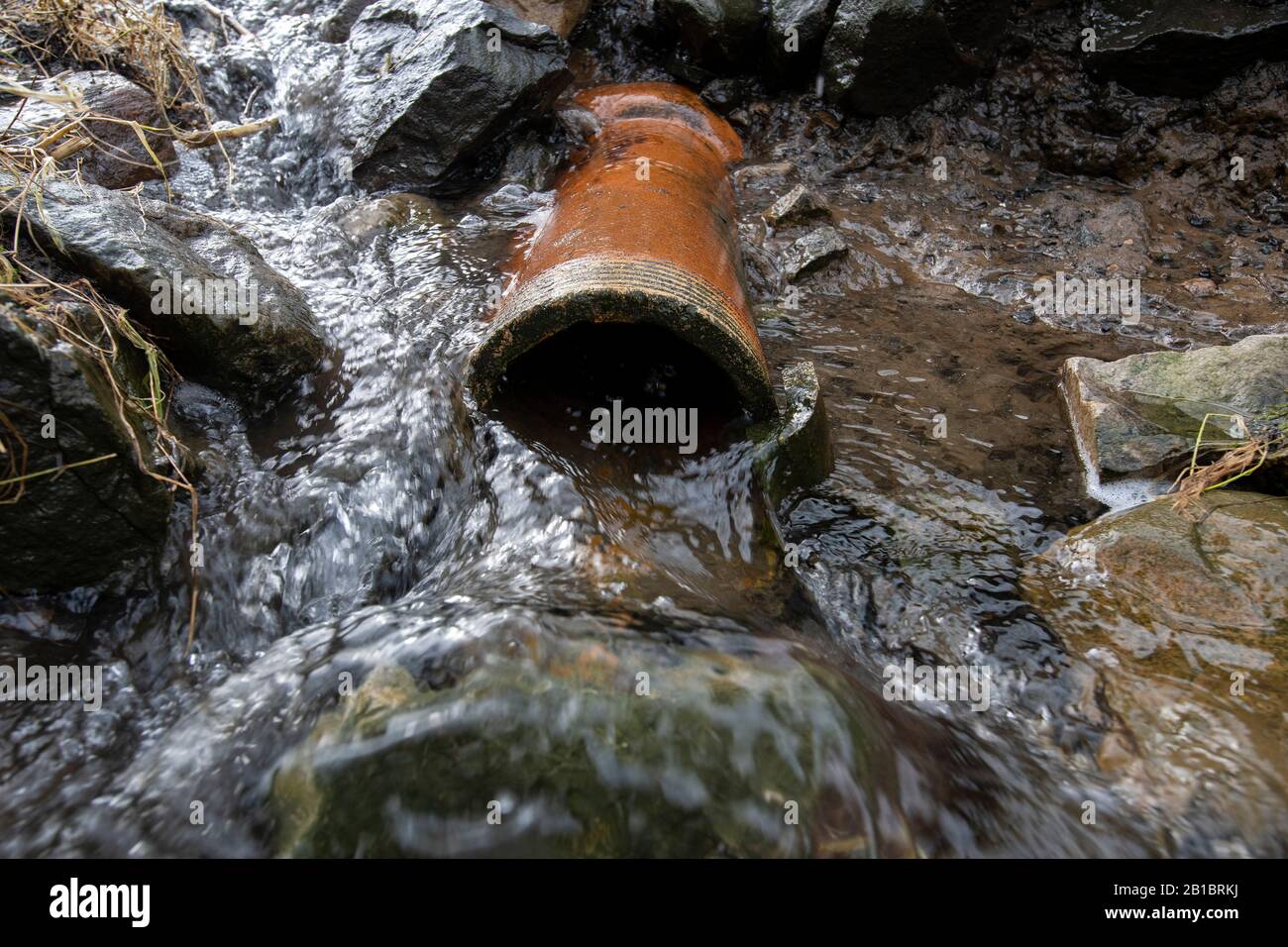 Acqua che fuoriesce da un drenaggio stradale. Yorkshire, Regno Unito. Foto Stock