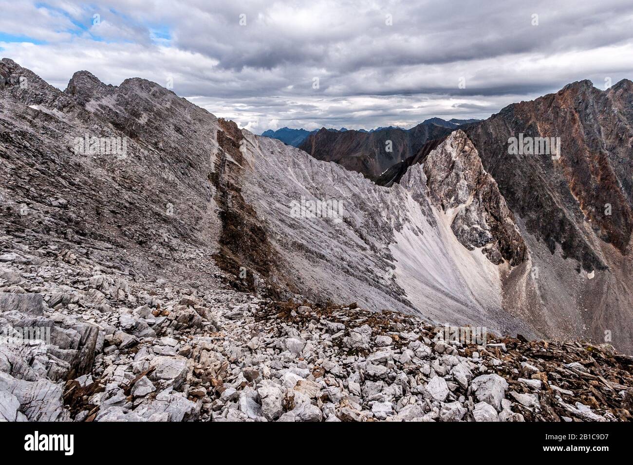 Vista su un crinale roccioso con pietre bianche e marroni. Rocce senza vegetazione. Nuvole nel cielo. Orizzontale. Foto Stock