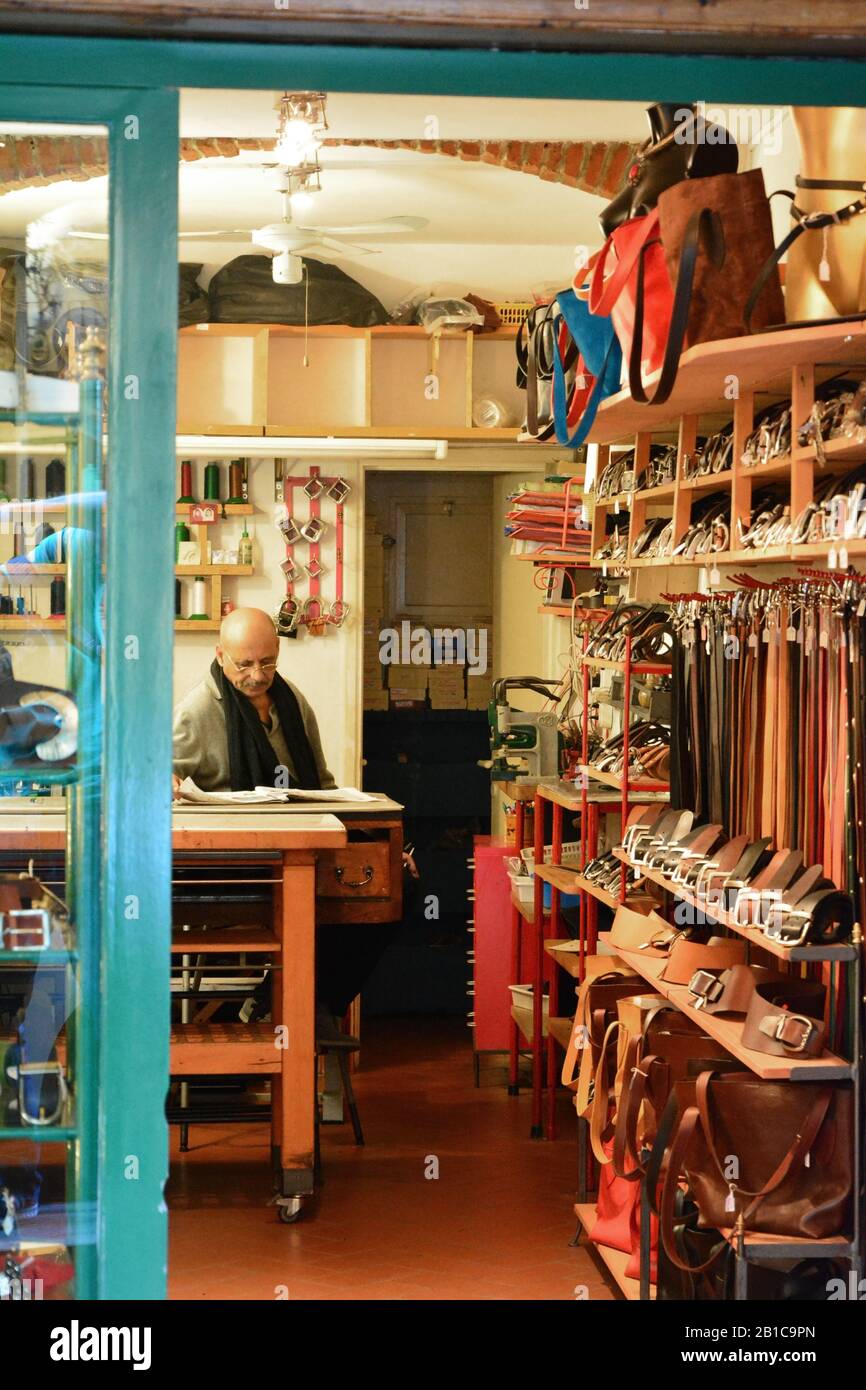 Ottobre 2016 - Ledershop worker all'interno di un negozio di pelletteria nella regione Toscana d'Italia, con vari articoli in vendita come cinture, borse e borse Foto Stock