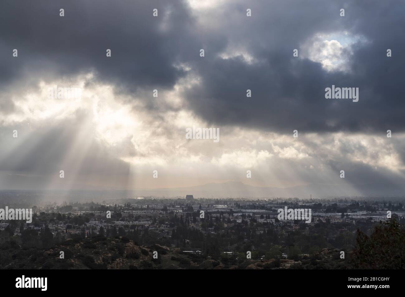 Raggi di sole che si infrangono attraverso nuvole di tempesta invernale sopra la Valle di San Fernando a Los Angeles, California. Foto Stock