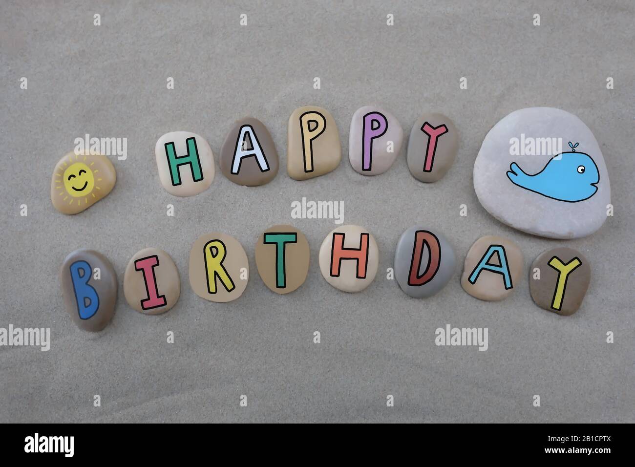 Buon compleanno con lettere di pietra colorate e divertenti sulla sabbia  della spiaggia Foto stock - Alamy