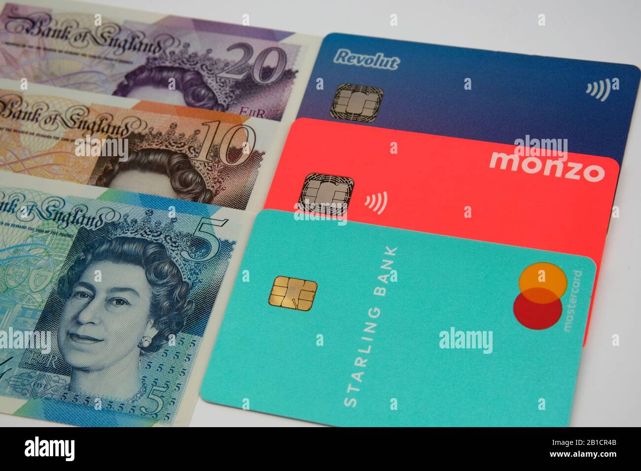 Starling, Monzo, carte bancarie Revolut sulle nuove banconote in sterline. Concetto per evidenziare gamma di colori simili delle fatture e della banca britanniche. Foto Stock