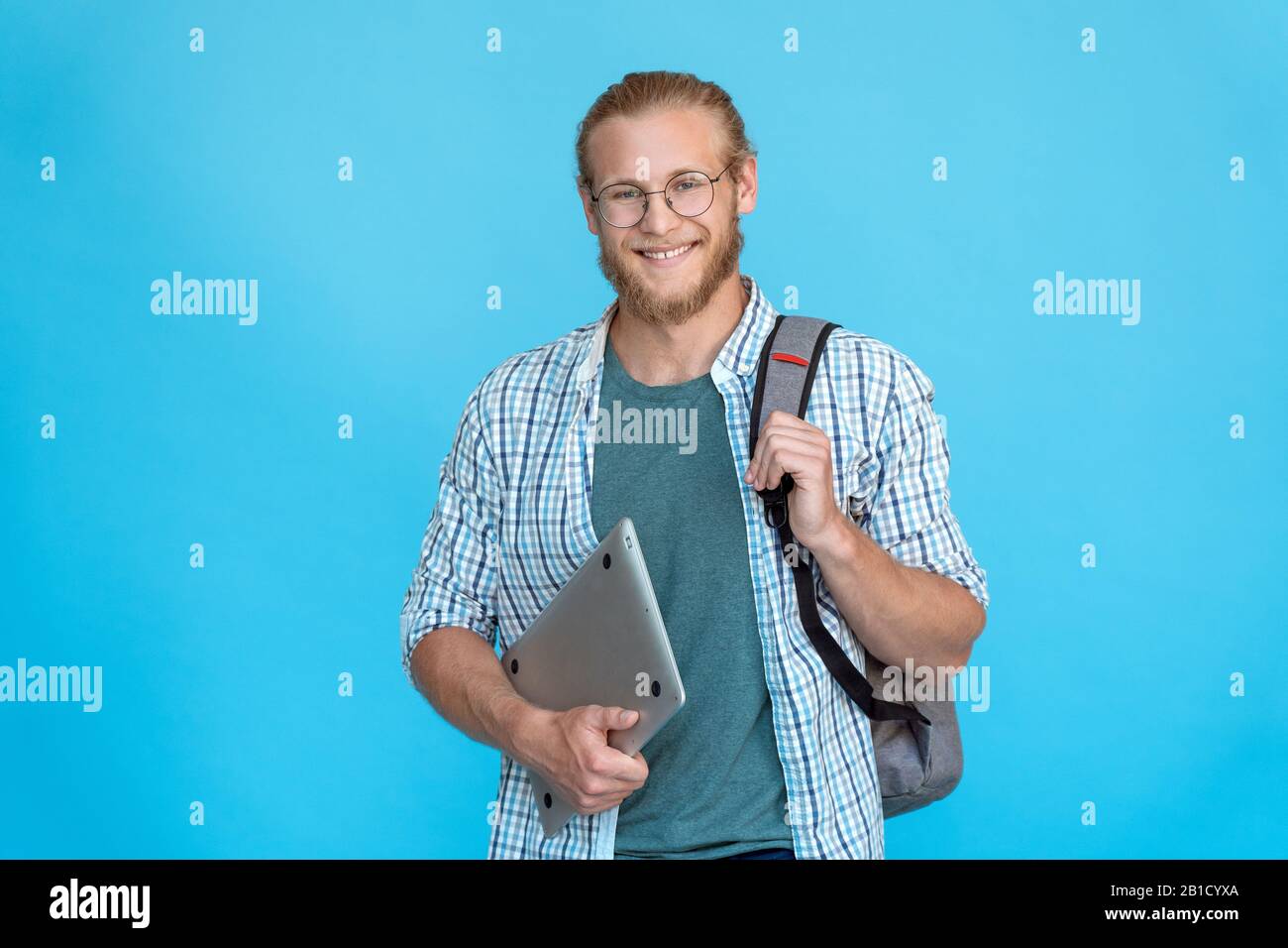 Sorridente giovane studente del college bearded indossare occhiali tenere moderno laptop copia spazio Foto Stock