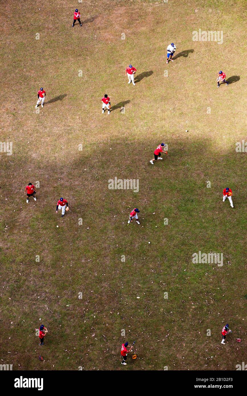 Un gruppo di giocatori di baseball che indossano una maglia rossa sta praticando la loro abilità di lanciatore della sfera sul campo da una prospettiva aerea. Foto Stock